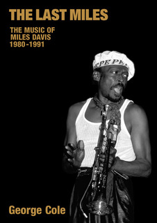 photo of Miles holding trumpet in a string vest and cap looking back over left shoulder