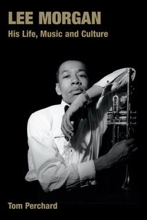 Photo of Morgan in relaxed pose with left arm resting on upright trumpet