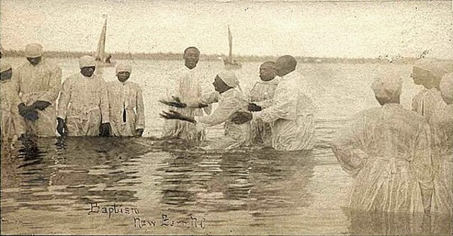 Postcard entitled" Wade in the water" showing a sepia photograph depicting a river baptism in New Bern, North Carolina, around 1900.