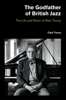 photo of Tracey sitting, facing out, on piano stool in front of a grand piano