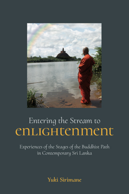 monk on riverbank across from a Stupa and rainbow