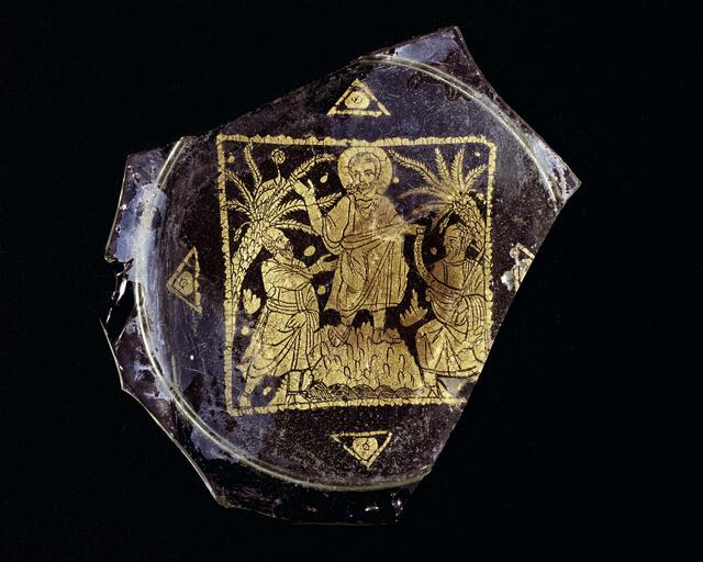 Fragment of a shallow Roman blown glass bowl showing Christ giving a scroll to two figures. The scroll reads “DOMINVS LEGE[M] DAT,” which translates to “the Lord giving the law.” The object is held in the Toledo Museum of Art. 