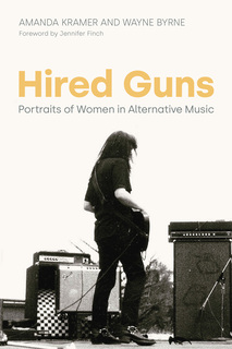 photo of female guitarist standing on outdoor stage surrounded by loudspeakers